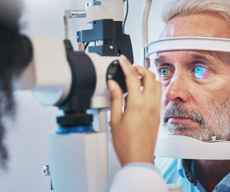 An older man undergoes an eye examination using a slit lamp at an optometrist's office - Eye allergy