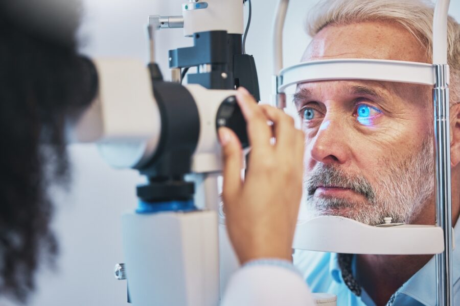 An older man undergoes an eye examination using a slit lamp at an optometrist's office - Eye allergy