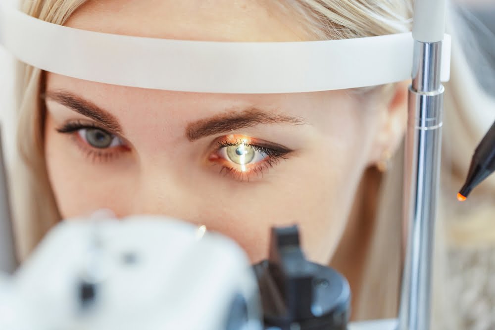 A close-up view of a woman undergoing an eye examination with a slit lamp machine, her eye illuminated by a focused light - Glaucoma Treatment A close-up view of a woman undergoing an eye examination with a slit lamp machine, her eye illuminated by a focused light - Glaucoma Treatment