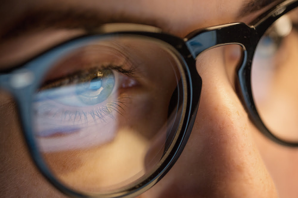 A close-up of a person's eyes wearing glasses, with the reflection of a computer screen visible in the lenses - Computer Vision Syndrome A close-up of a person's eyes wearing glasses, with the reflection of a computer screen visible in the lenses - Computer Vision Syndrome