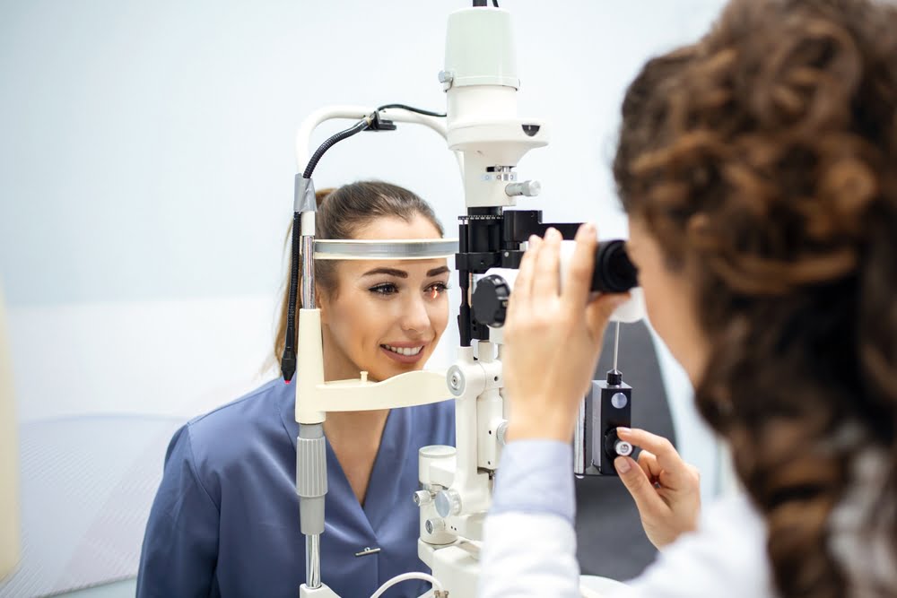 A woman undergoes an eye exam using a slit lamp microscope, smiling at the optometrist - Myopia Control A woman undergoes an eye exam using a slit lamp microscope, smiling at the optometrist - Myopia Control