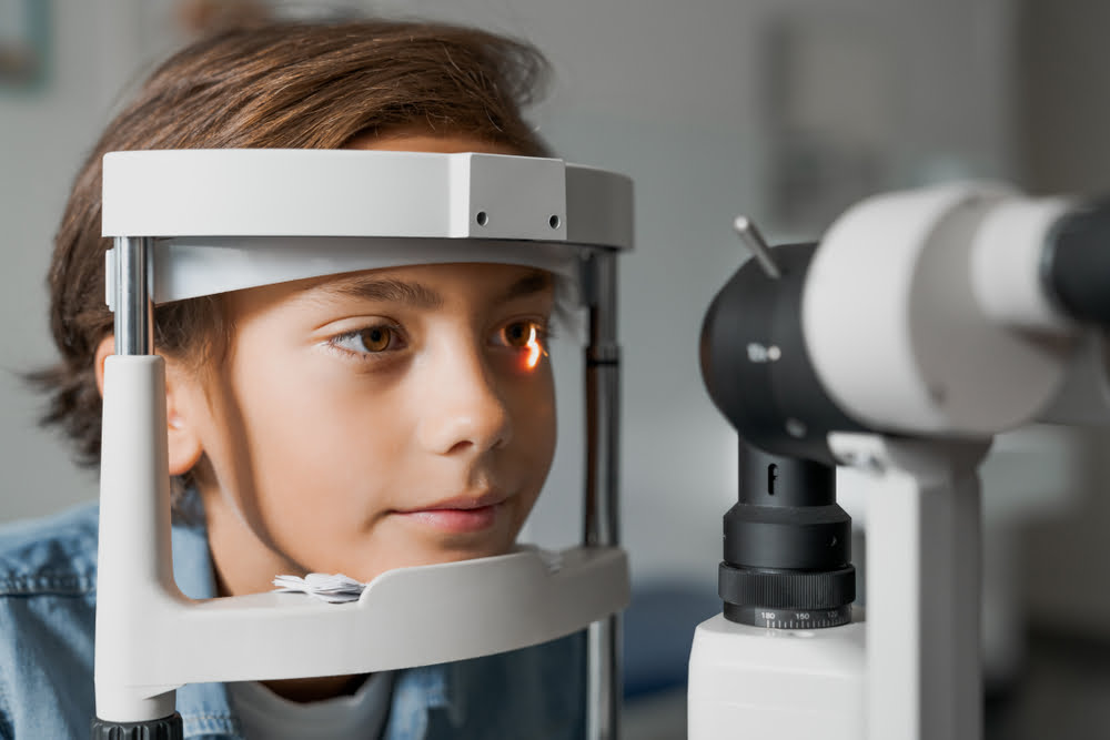 A child undergoing an eye examination using a slit lamp machine in an optometry clinic - Pediatric eye exams
